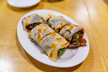 Beef roll pancake with scallions, thinly sliced braised beef wrapped in crispy Chinese flatbread, traditional Taiwanese snack