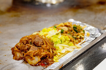 Beef, chicken, and stir-fried cabbage on foil, served hot on a Taiwanese teppanyaki grill with onions and savory sauce