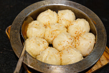 Close-up of sheng jian bao with a bite revealing juicy pork filling, crispy bottom and soft steamed top, Shanghai street snack