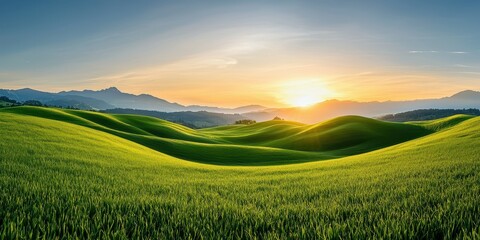 Breathtaking sunset over lush green hills with distant mountains.