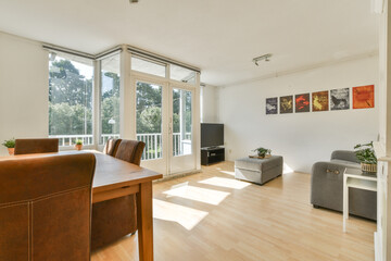 A spacious living room featuring contemporary furniture, large windows allowing ample sunlight, and vibrant wall art that enhances the atmosphere.