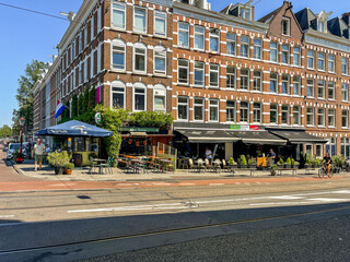 A bustling city street scene featuring outdoor cafes, historic architectural buildings, and lively...
