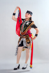 A Jathilan dancer from Central Java poses gracefully in colorful traditional costume, holding red scarves as part of a vibrant cultural performance rooted in Indonesian heritage.