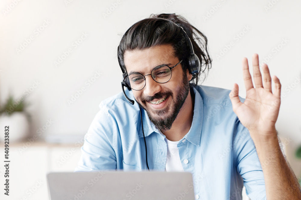 Poster distant communication. happy western man in headset waving hand at laptop camera while making video 