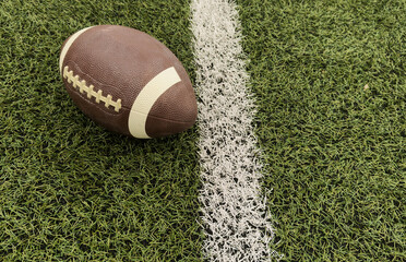 American football ball on green grass field background.