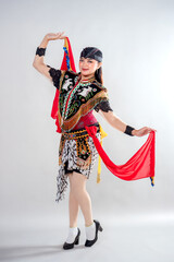 A Javanese female dancer in traditional Jathilan attire performs a graceful pose with red scarves,...