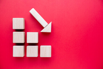 Wooden toys arranged in the shape of a graph and arrows pointing down, economic and business downturn concept