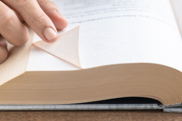 Close-up of a man's fingers folding down the corner page of a book, dog ear
