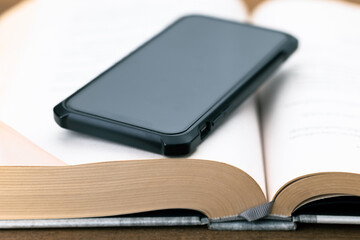 Closeup a smartphone that placed on the opened book, compare the contents on the phone with a book,...