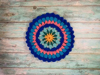 Crocheted mandala doily on wooden background handmade decor art craft photo	
