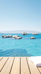 Obraz premium white towel on wooden deck overlooking a tranquil turquoise sea with rocks