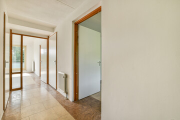 An expansive hallway featuring light-colored walls and wooden doors, illuminated by natural light, creating a warm ambiance in the space.