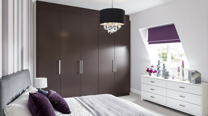 modern bedroom interior with built-in dark brown wardrobe and white dresser