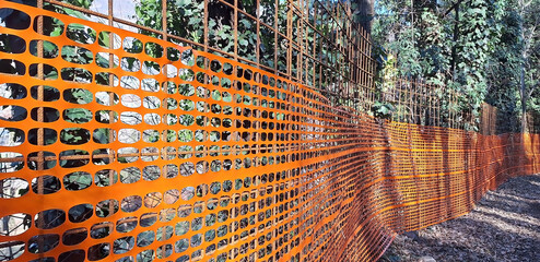 Orange fence in the form of a grid. Closed Park area. Panorama.