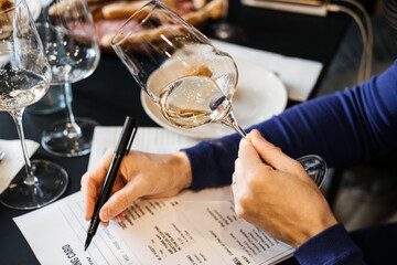 Woman selecting a wine during a wine workshop session at a shared table. Wine workshop, food literacy, decision making, group wine class