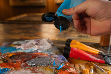 The artist`s hand, which squeezes the oil paint from the tube into the palette