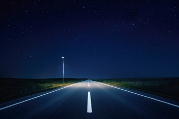 Starry night sky over empty road with single streetlamp