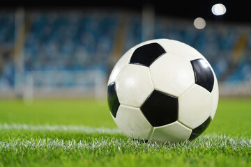Soccer ball on grass field under stadium lights awaiting kickoff