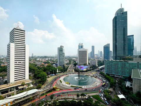 View of Jakarta city centre, the central business district and the famous Bundaran HI roundabout with Jakarta skyscrapers and the traffic on the road, under the sunny blue sky.