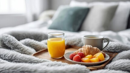 A cozy breakfast tray with coffee, orange juice, a croissant, and fresh fruit rests on a fluffy blanket. The bed is inviting and peaceful.