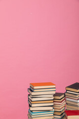 Stacks of old books for teaching in the library on a pink background at school
