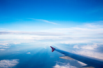 Aerial view of cloud blue sky and plane wing view through the airplane window.