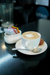 Cup of coffee with heart-shaped latte art served alongside a single cookie, creating a warm and inviting coffee break moment.