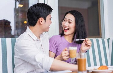 Joyful couple enjoying drinks and dessert at a cozy café during a leisurely afternoon
