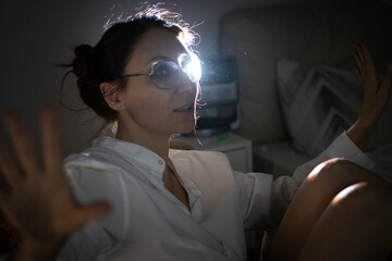 Woman gesturing with hands in dark room with bright light