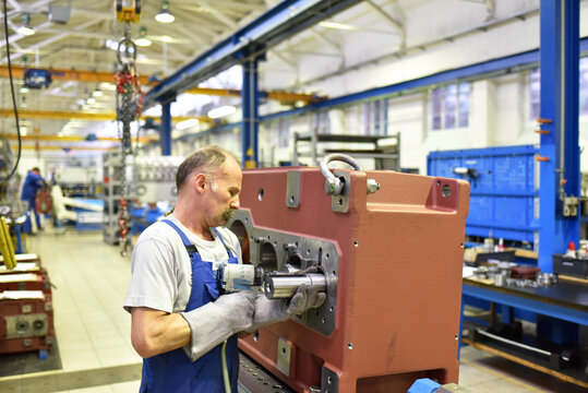 older worker in mechanical engineering - industrial factory for the production of steel gearboxes
