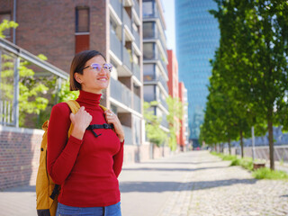 Fototapeta premium Tourist woman explores modern Frankfurt, walking through vibrant streets with contemporary architecture, skyscrapers, and urban spaces, enjoying lively atmosphere of modern side.