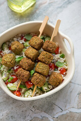 Falafel skewers with couscous and vegetables, vertical shot on a grey granite background, high...
