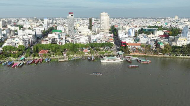 Drone view of vibrant cityscape of Can Tho city with a focus on the bustling Ninh Kieu Wharf and the tour boats along the river in Can Tho, Vietnam.
