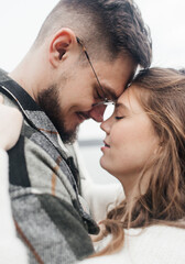 Young couple in stylish clothes on a walk. Romantic date outdoors. Walk, kisses and hugs