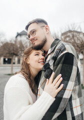 Young couple in stylish clothes on a walk. Romantic date outdoors. Walk, kisses and hugs