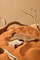 Vertical photo of rough pieces of wood placed on uneven sandy surface. Large branches of dead...