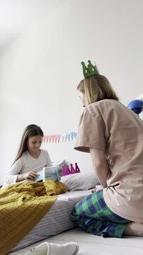 Little girl opens gift on birthday morning with mom