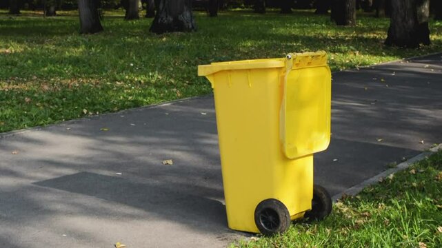 Yellow trash bin in a city park.