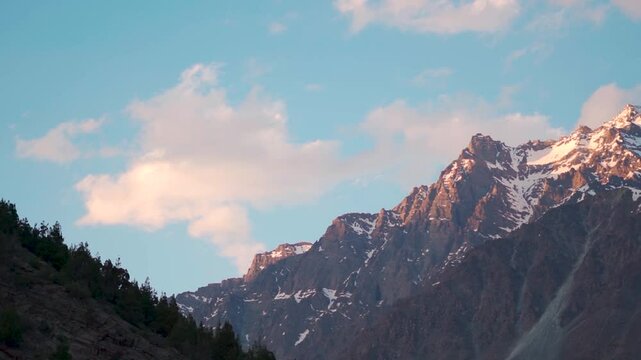 Orange clouds above the snowy Himalayan mountain peak during the sunset in summer season as seen from Darcha in Lahaul Valley, Himachal Pradesh, India. Sunset in the Himalayas background.