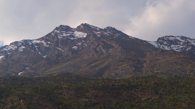 Landscape shot of clouds above the snowy Himalayan mountain peaks during a cloudy day as seen during the summer season from Jispa village in Lahaul Valley, Himachal Pradesh, India. Natural background.