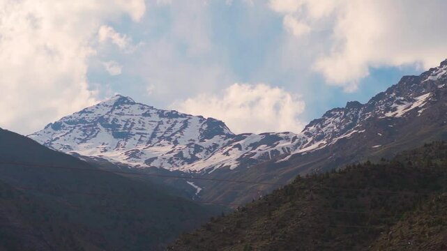 Clouds above the snowy Himalayan mountain peak with blue sky as seen from Jispa village in Lahaul and Spiti district, Himachal Pradesh, India. Scenic view of the Himalayan mountain ranges.