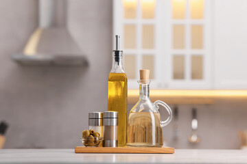 Bottles of salad dressings, salt, pepper and olives on white table in kitchen