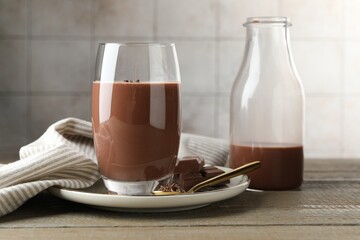 Tasty chocolate milk with shavings and pieces on wooden table