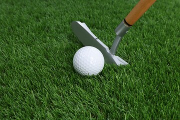 Golf ball and club on green grass, closeup