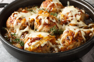 Baked French Onion Meatballs with caramelized onions and Gruyere cheese closeup on the pan on the table. Horizontal