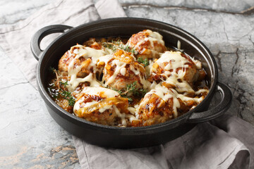 Hot French onion meatballs are inspired by the iconic soup, complete with caramelized onions and Gruyere cheese closeup on the pan on the table. Horizontal