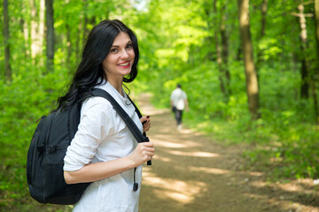 Young woman tourist. Female is walking with a backpack on a green forest.