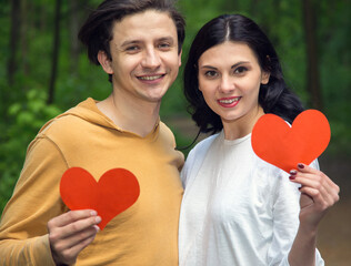 Loving couple. Man and woman holding a red heart in their hands - the concept of a symbol of love...