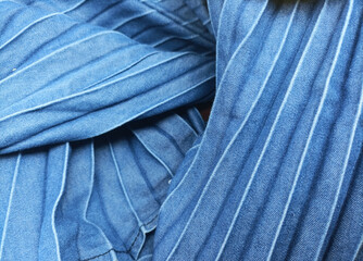 Closeup of jeans fabric surface texture pattern design with straight crimped lines. Top view of abstract blue denim jeans textile fabric, circular and wrinkled for wallpaper, 3D, web and background.