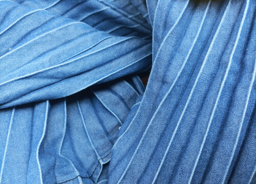 Closeup of jeans fabric surface texture pattern design with straight crimped lines. Top view of abstract blue denim jeans textile fabric, circular and wrinkled for wallpaper, 3D, web and background.